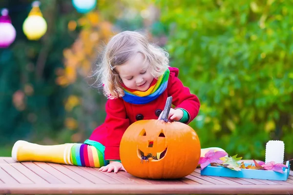 Little girl carving pumpkin at Halloween