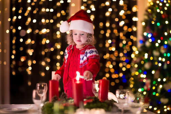 Маленькая девочка зажигает свечи на рождественском ужине
