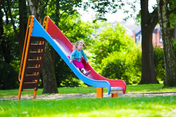 Little girl sliding on a playground — 图库照片