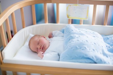 Newborn baby boy in hospital cot clipart