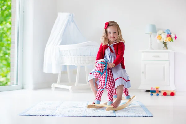 Liten flicka rider en leksak häst — Stockfoto