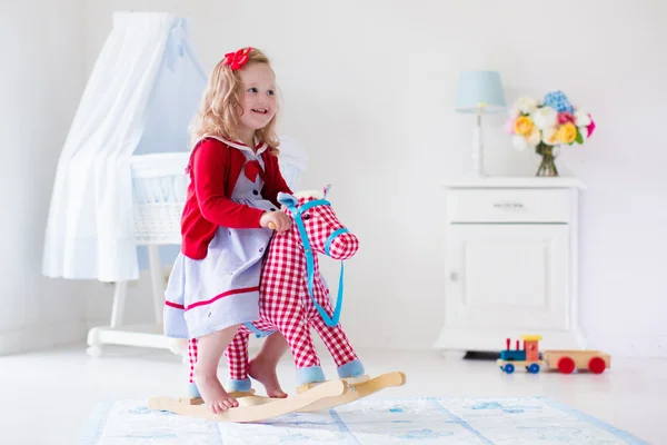 Little girl riding a toy horse — Stock Photo, Image