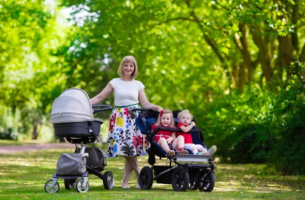 Woman with kids in stroller in a park — Stok fotoğraf