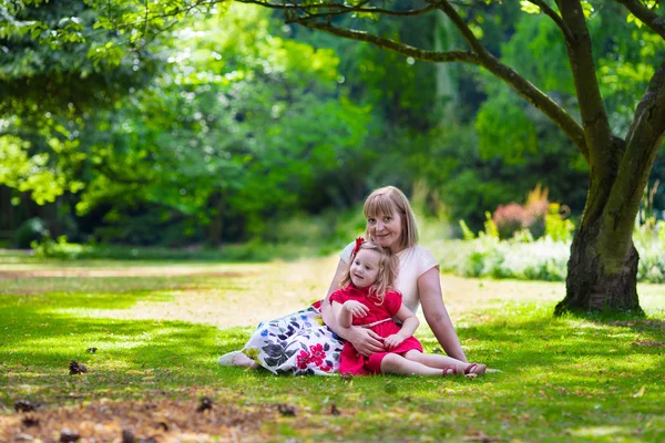 Beautiful woman and little girl having picnic in a park — ストック写真