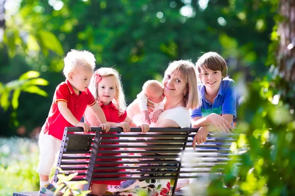 Family with kids relaxing on a park bench — Stok fotoğraf