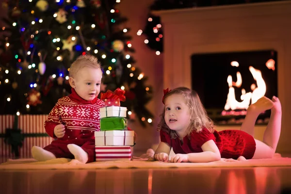 Niños abriendo regalos de Navidad en la chimenea —  Fotos de Stock