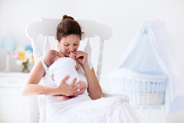 Young mother and newborn baby in white bedroom