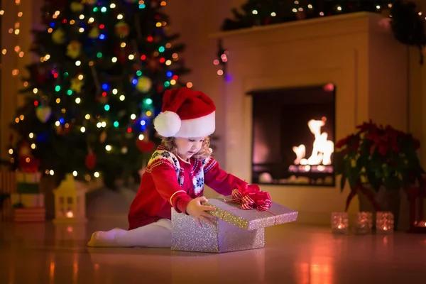 Kinderen openen Kerstcadeaus bij open haard — Stockfoto