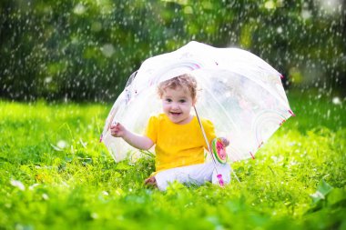 Little girl with colorful umbrella playing in the rain