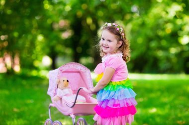 Küçük kız bir oyuncak stoller wth bebek iterek