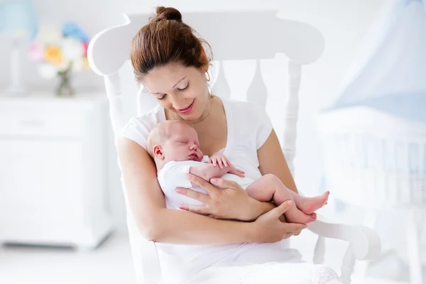 Jonge moeder en pasgeboren baby in witte slaapkamer — Stockfoto