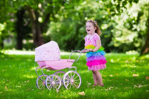 Niña empujando un juguete stoller wth muñeca — Foto de Stock