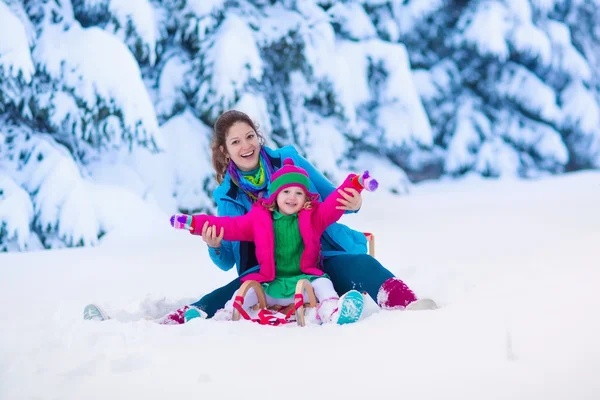 Катание на санках матери и ребенка в снежном парке — стоковое фото