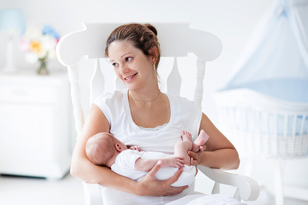 Young mother and newborn baby in white bedroom