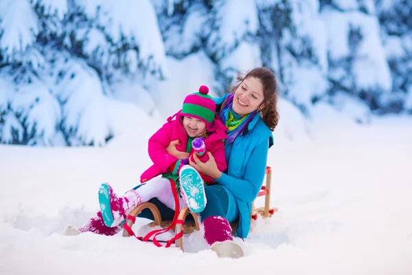 Madre e hijo en trineo en un parque cubierto de nieve — Foto de Stock