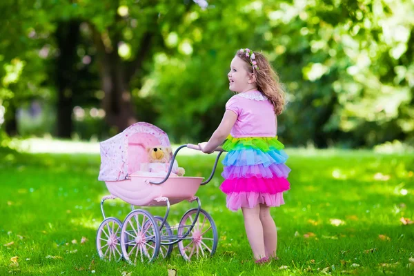 Niña empujando un juguete stoller wth muñeca — Foto de Stock