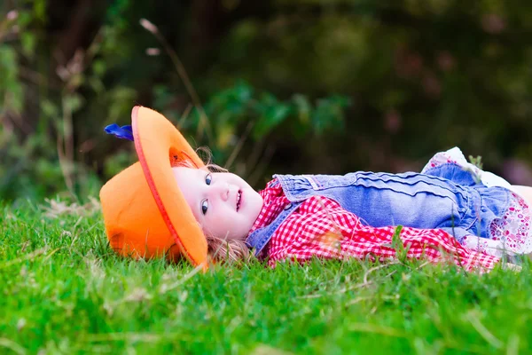 Little girl playing with toy horse in cowboy costume — ストック写真