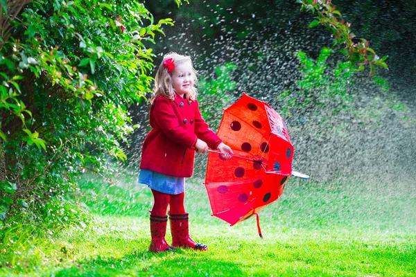 Menina em casaco vermelho jogando na chuva de outono — Fotografia de Stock