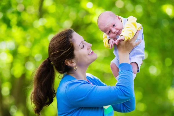 Mother holding newborn baby in a park — Stock Photo, Image