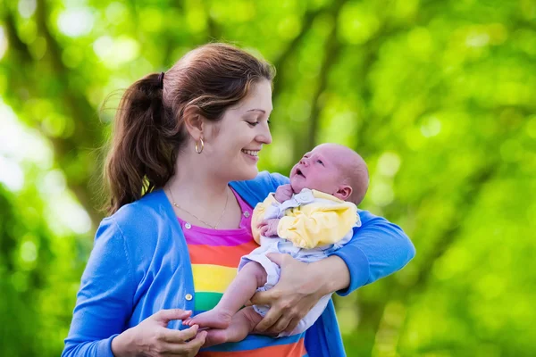 Moeder bedrijf pasgeboren baby in een park — Stockfoto