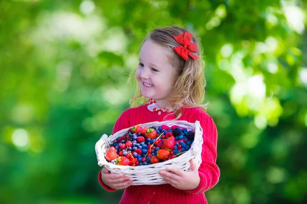 Little girl with fresh berries in a basket — Stok fotoğraf