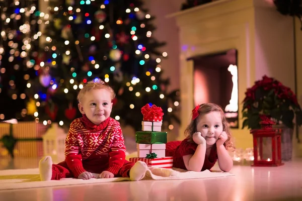 Barn öppnar julklappar vid spisen — Stockfoto