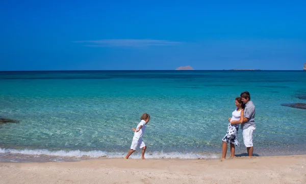 Hermosa familia joven caminando en una playa tropical —  Fotos de Stock