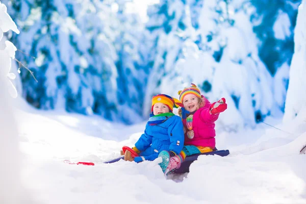 Kids having fun on a sleigh ride in snow — Stock Photo, Image