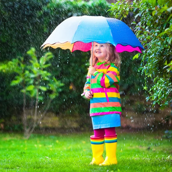 Menina brincando na chuva sob guarda-chuva colorido — Fotografia de Stock