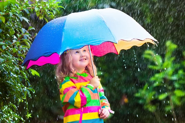 Niña jugando bajo la lluvia bajo el paraguas — Foto de Stock