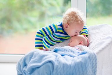 Little boy kissing newborn baby brother clipart