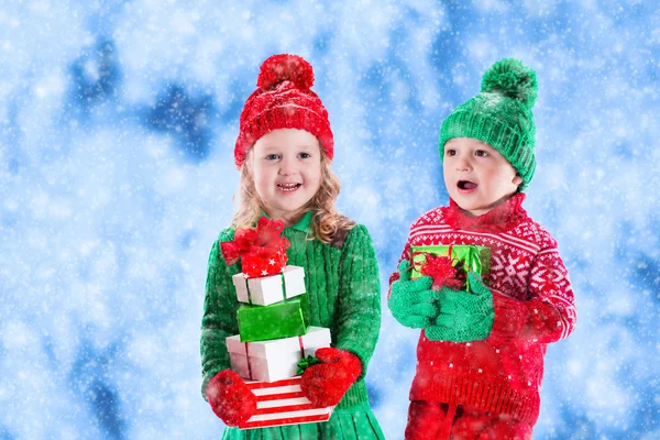 Kids with Christmas presents in winter park in snow — Stock Photo, Image