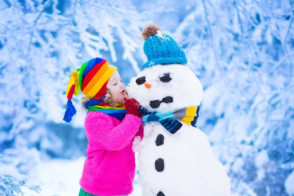 Küçük kız bir kar adam kışın bina