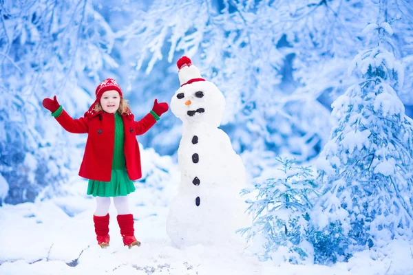 Bambina che costruisce un uomo di neve in inverno — Foto Stock