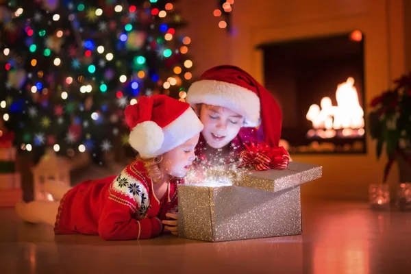 Παιδιά άνοιγμα χριστουγεννιάτικα δώρα στο τζάκι — Φωτογραφία Αρχείου