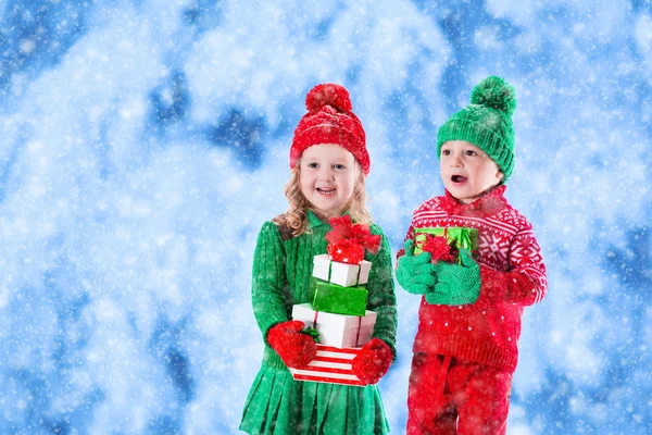 Kids with Christmas presents in winter park in snow — Stock Photo, Image