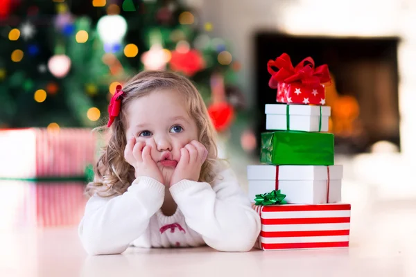 Little girl opening Christmas presents at fire place — Stock Photo, Image