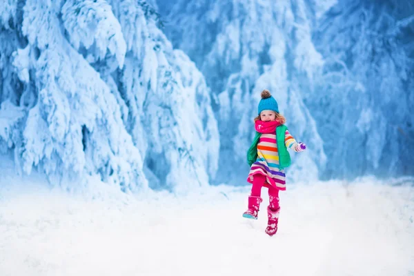 Kleines Mädchen spielt im verschneiten Winterwald — Stockfoto