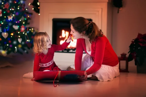 Mother and daughter reading on Christmas eve at fire place