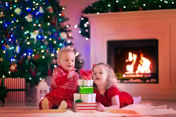 Kids opening Christmas presents at fire place — Stok fotoğraf