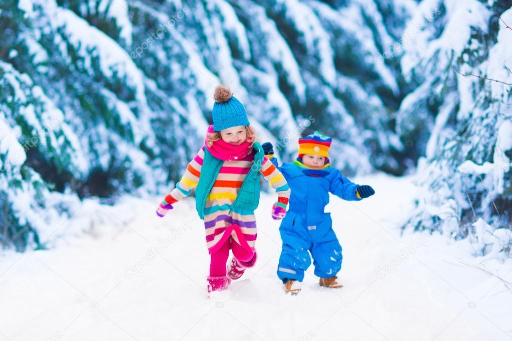 Little girl playing in snowy winter forest