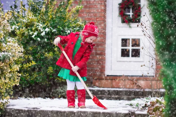 Ragazzina che spala neve in inverno — Foto Stock