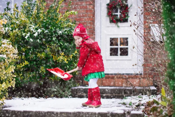 Kleines Mädchen schaufelt im Winter Schnee — Stockfoto