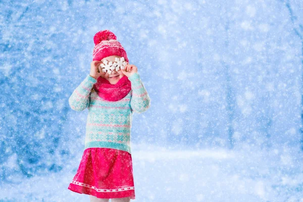 Menina brincando com flocos de neve de brinquedo no parque de inverno — Fotografia de Stock