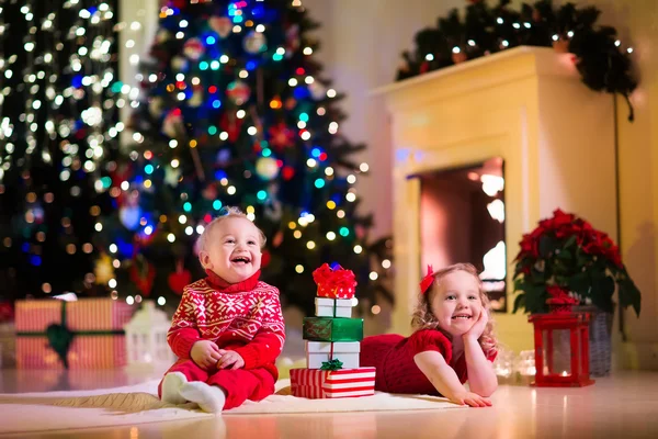 Kids opening Christmas presents at fireplace — Stock Photo, Image