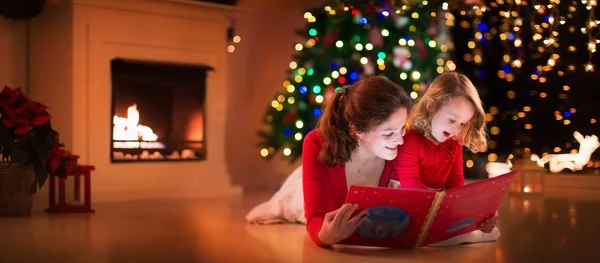 Madre e hija leyendo en la chimenea en Nochebuena — Foto de Stock