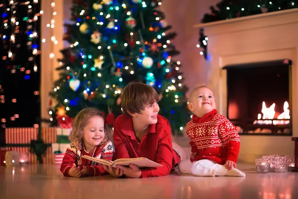 クリスマス ・ イヴに暖炉のそばで遊んでいる子供 ストック写真