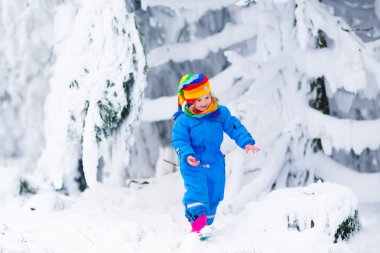 Küçük kız kışın karla oynuyor.