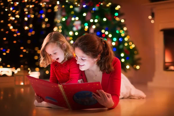 Moeder en dochter lezen bij de open haard op kerstavond — Stockfoto