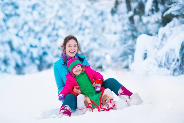 Madre e hijo en trineo en un parque cubierto de nieve — Foto de Stock